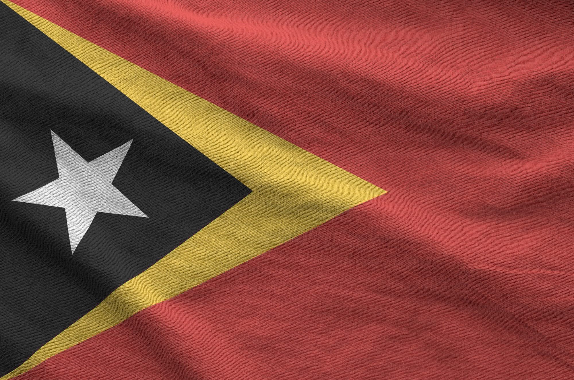 Timor Leste flag depicted on folded wavy fabric of old cloth